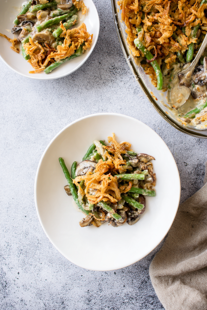 Vegan green bean casserole with crispy onions served in a white bowl